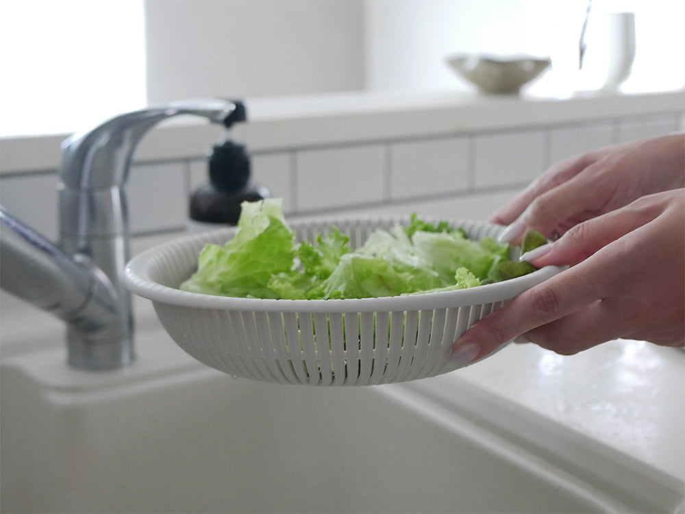 シンクの上に置かれたマーナのざるボウル21cm。ポリプロピレン製で耐熱・耐冷性があり、食材の準備や盛り付けに最適なプラスチック製食器です。