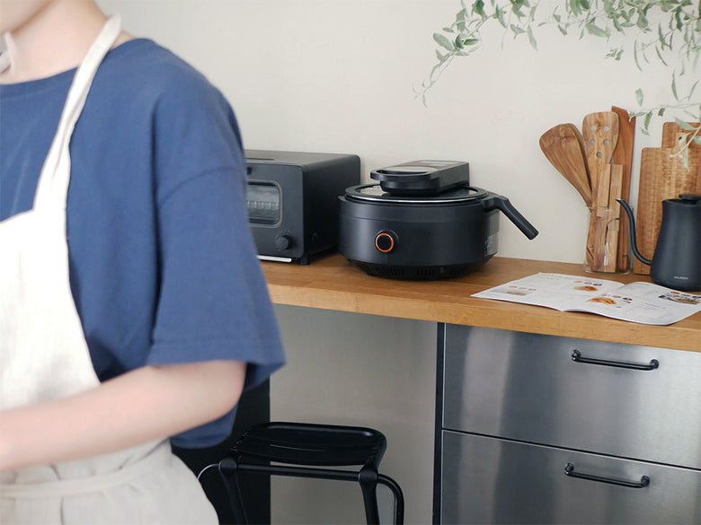 AINXの全自動調理スマートオートクッカー本体とガラス蓋がキッチンカウンターに置かれている様子
