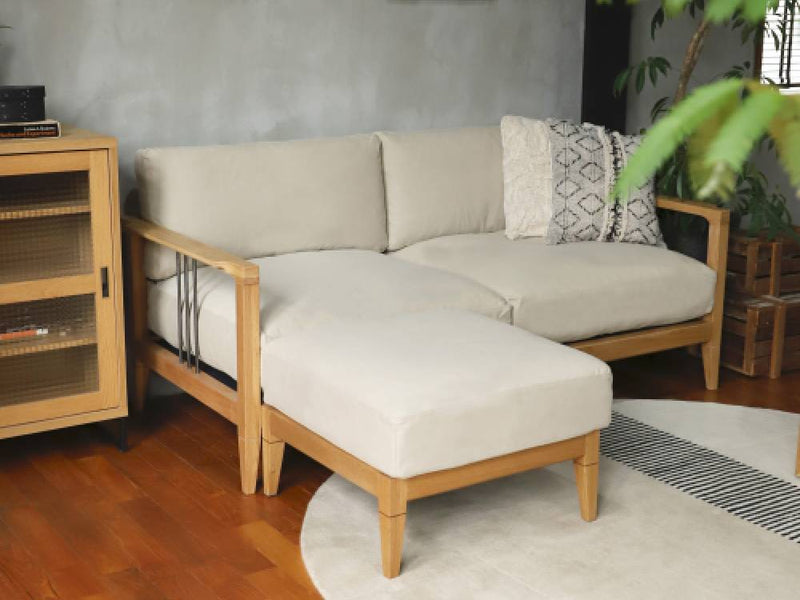 アデペシュのソロ2.5シートソファーとオットマンが木製のリビングルームに配置され、クッションや投げ枕で快適な居住空間を演出しているインテリア写真