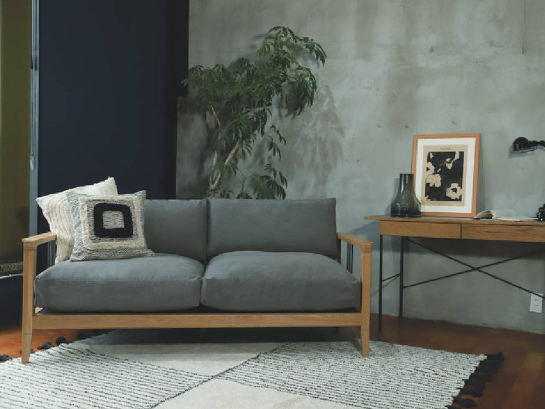 リビングルームに配置されたグレーのソロ2.5シートソファーとクッション、ハードウッドフロアが特徴の家具