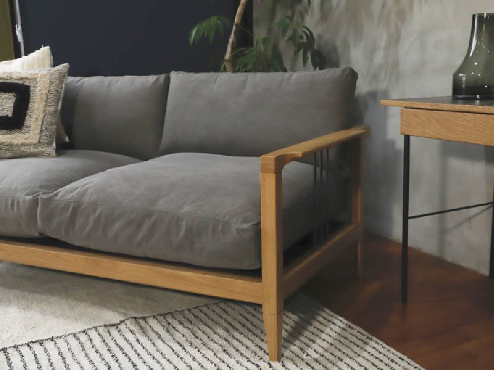 ハードウッド製のアデペシュソロソファがリビングルームに配置され、ナチュラルなデザインとカラフルなクッションが特徴です