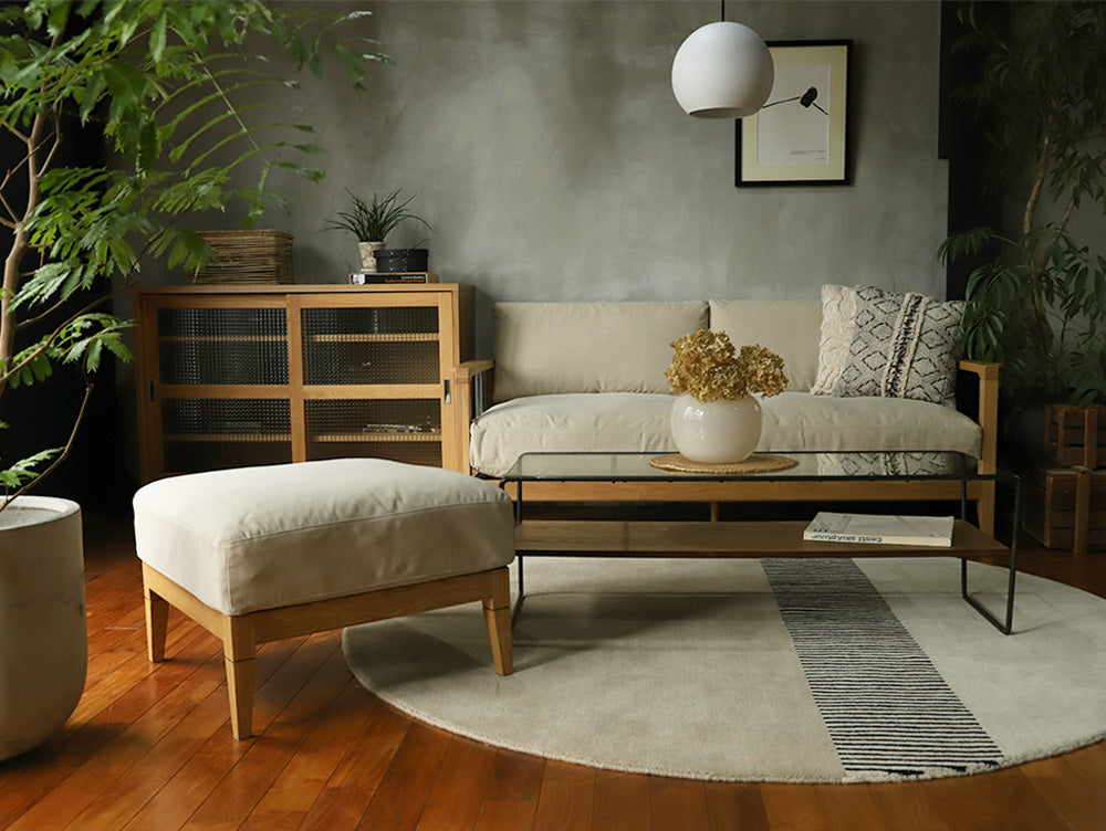 ブラウンの木製床に配置されたアデペシュ製ソロ2.5シートソファーとオットマン