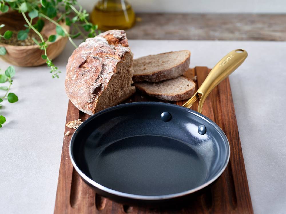 グリーンパンのストゥディオシリーズキャセロール、ソースパン、ミルクパンがキッチンカウンターに並べられた調理器具セットの写真