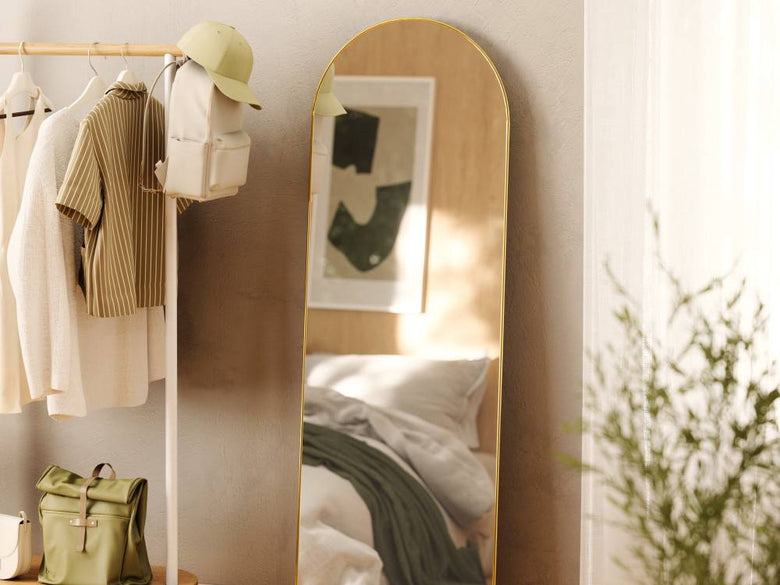 フーバ アーチド リー二ングミラーがバッグ、ハンガー、ランプなどとともに配置された室内の写真