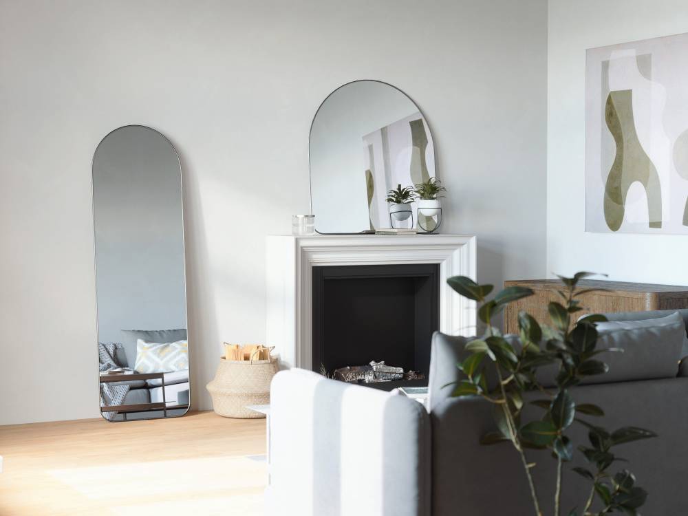 灰色を基調としたリビングルームのインテリアデザイン。フーバ アーチド リー二ングミラーや家具、照明、絵画フレーム、投げ枕が調和して配置されている
