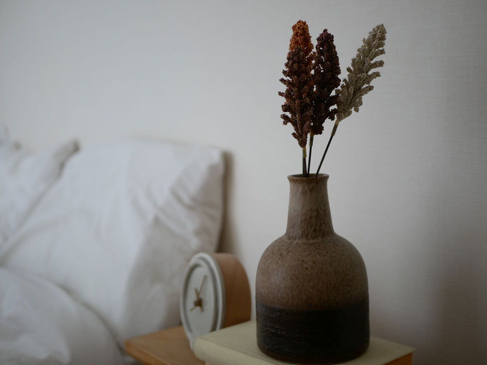 自然素材の家具上にセラミックの花瓶で飾られたアデペシュのアーティフィシャルフラワー