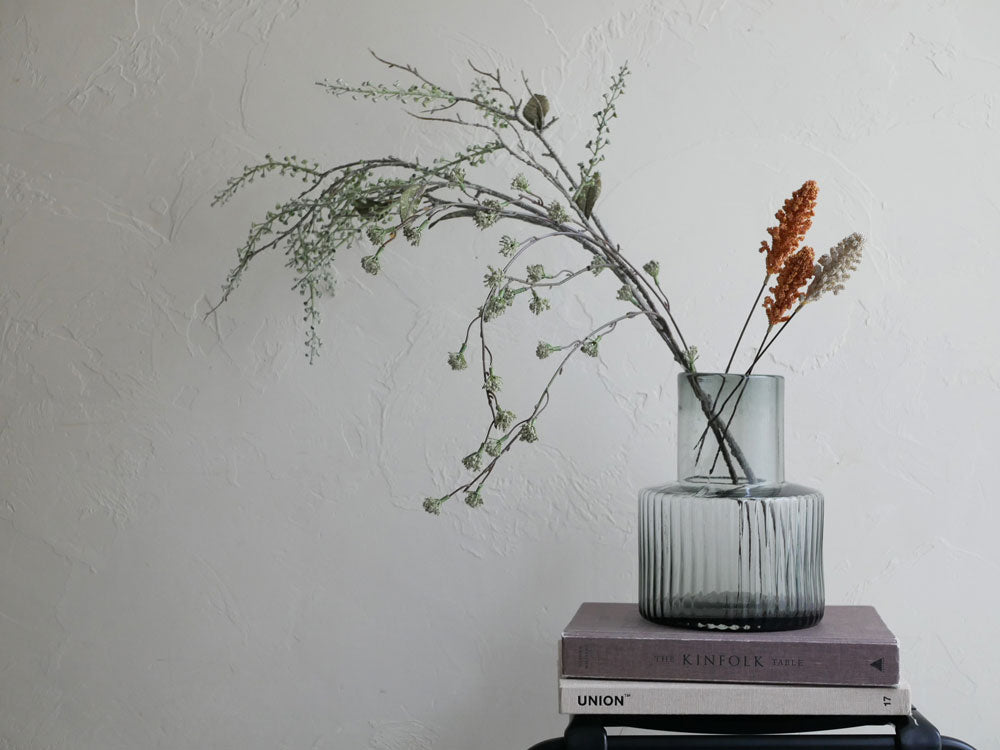 シルバーのシリンダー花瓶にアーティフィシャルフラワーと枝が美しく配されたフラワーアレンジメント