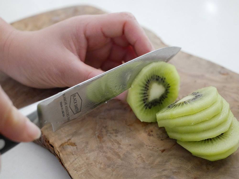 ダマスカス鋼製TOOLSナイフシリーズがカッティングボード上に果物とともに並べられているキッチンの様子