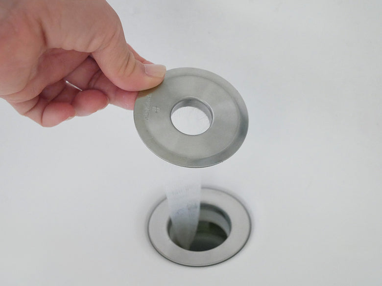 洗面台の排水口に取り付けられたヒューバス HUBATH 洗面台ヘアーキャッチャー。銀色のステンレスとプラスチック製のパーツが特徴。