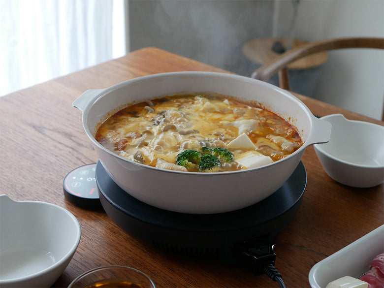 琺瑯と天然木を組み合わせたKINTOのIH卓上鍋KAKOMIでスープを調理している様子