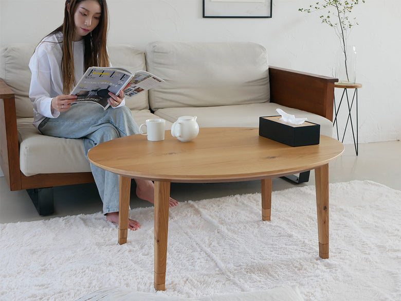 オーク材の高さ調節可能なこたつとソファ、コーヒーテーブルが配置されたリビングルームのインテリア