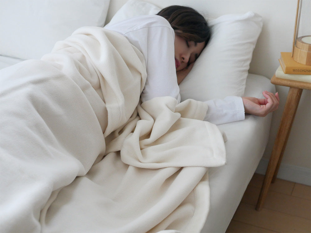 ココマニのオーガニックコットン100％毛布がシングルサイズのベッドに敷かれ、快適な寝具として整えられている様子