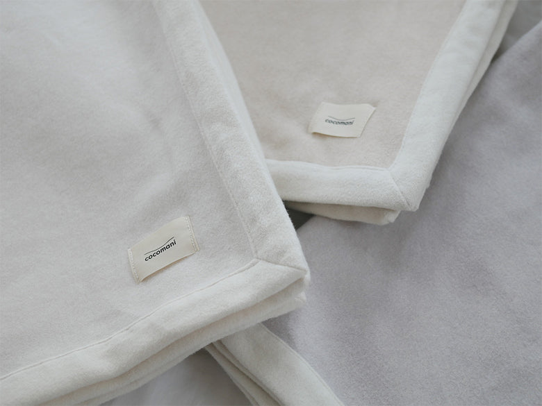 シングルサイズのココマニお肌に優しいオーガニックコットン毛布がアイボリー色で丁寧に折りたたまれた写真