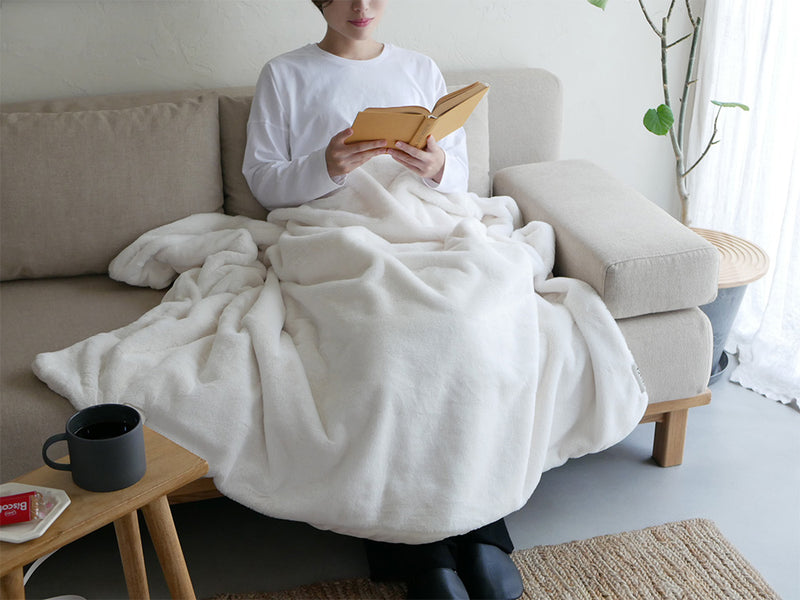 LALACAララカの洗えるなめらか素材ヒーターブランケットがリビングルームの家具やクッションと共に配置され、快適な空間を演出している様子