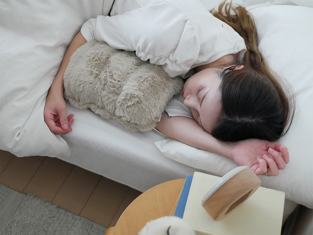 QUADSクワッズ蓄熱式湯たんぽtoronとクッション、枕、ベッドシーツなど快適な寝具が配置されたベッドの写真