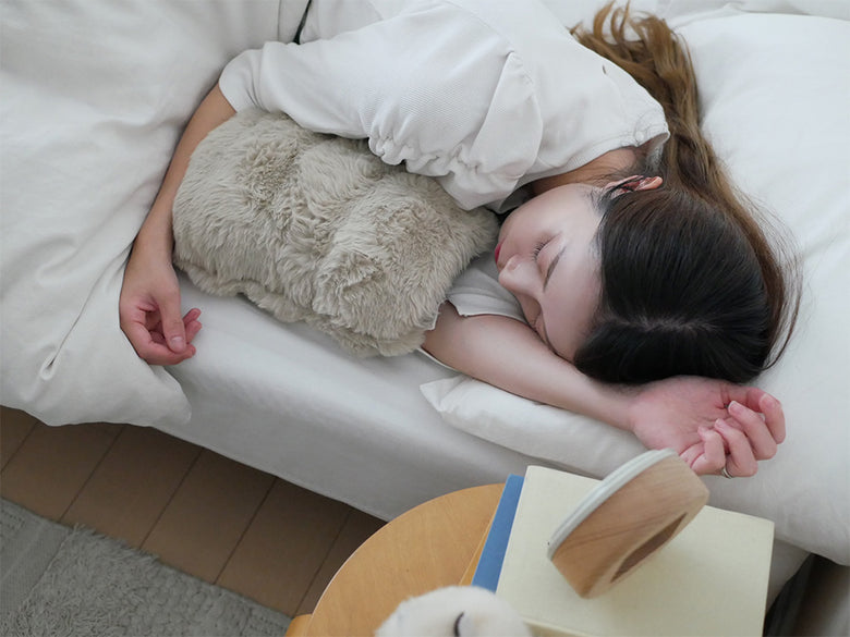 QUADSクワッズ蓄熱式湯たんぽtoronとクッション、枕、ベッドシーツなど快適な寝具が配置されたベッドの写真