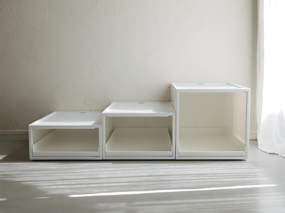 リビングルームに配置されたライクイットのオールホワイトクローゼットシステム引き出しオープントレータイプ、木製棚とグレーの木床が調和するデザイン