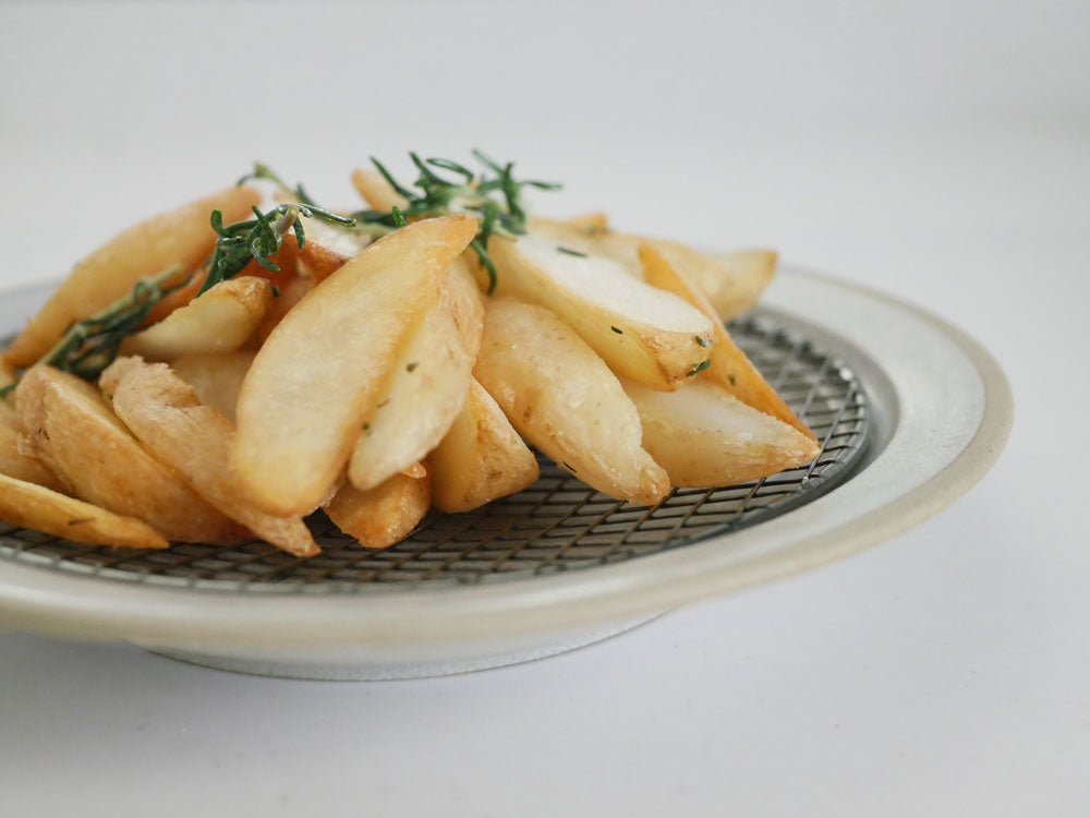 揚げたてのポテトウェッジが黒酸化網付きのamimeプレートに盛られた料理の画像