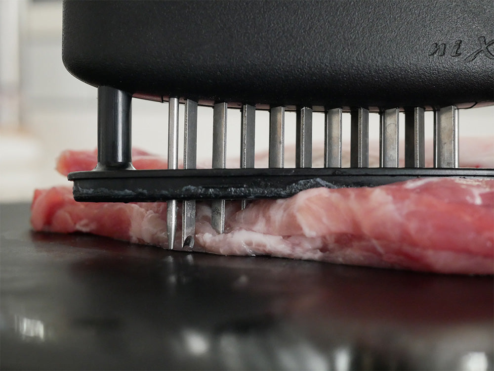 協和工業のニクサスプロ肉柔らかくする調理器具がまな板上で牛肉と豚肉をカットしている