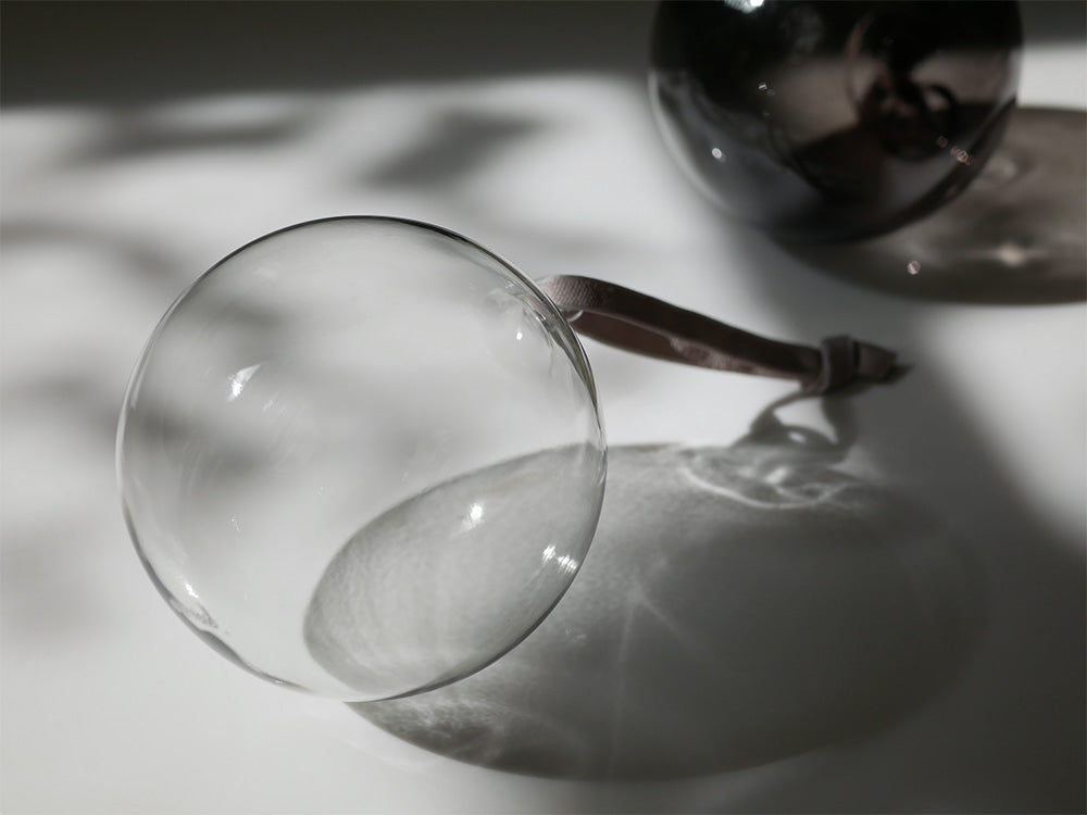 イッタラの無鉛ガラス製オーナメントセット。クリアとグレーの球体やホワイトバードが美しく並べられた静物写真