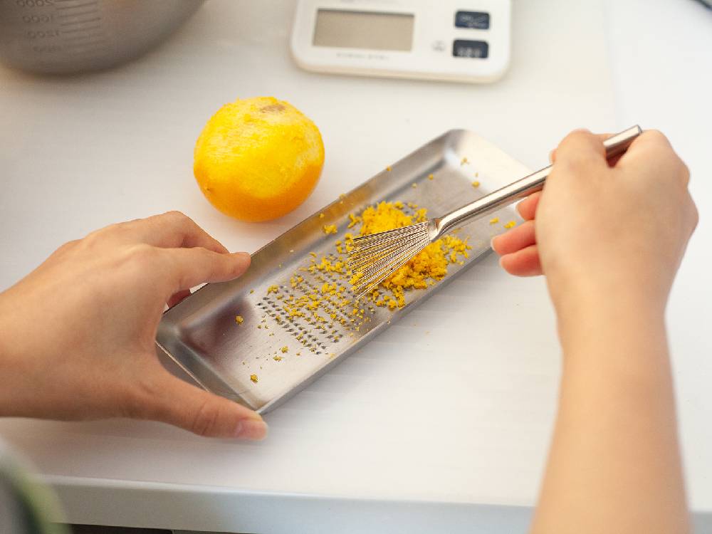 日本製の18-8ステンレス製EAトCOハケが、カッティングボードと果物などの食材とともにキッチン台に配置されています