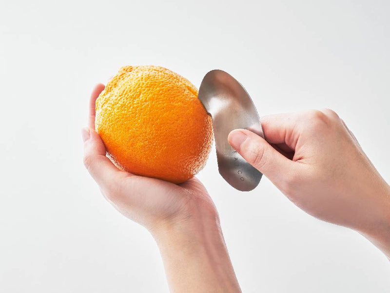 ステンレス製のEAトCOムクキッチンツールとグレープフルーツ、クレメンタイン、オレンジなどの柑橘類が並んでいる画像