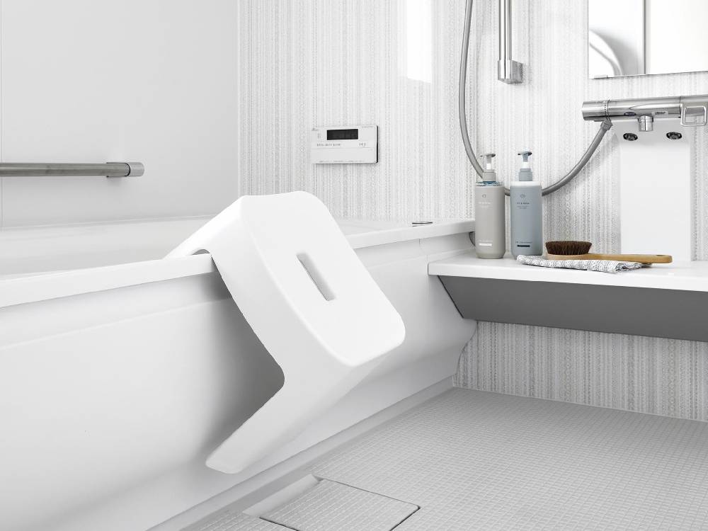浴室のタワー型マグネット風呂イスがバスタブ横のスチール壁面に取り付けられている様子。白色の製品が清潔感のあるバスルームに調和しています。