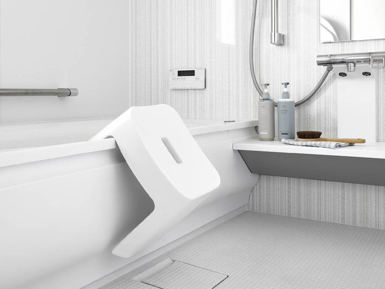 浴室のタワー型マグネット風呂イスがバスタブ横のスチール壁面に取り付けられている様子。白色の製品が清潔感のあるバスルームに調和しています。