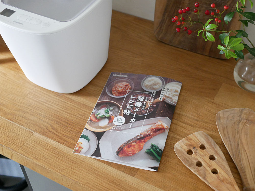 ビタントニオの初心者向け発酵メーカーと付属の容器やスプーン、レシピブックが木製のテーブル上に並べられている様子