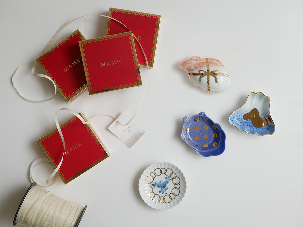 アマブロの吹墨富士形皿や丸散赤丸などの磁器製パーティーフェーバーが美しくボックスに収納された画像