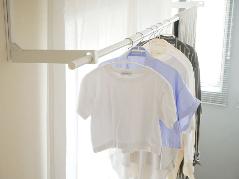 壁に取り付けたタワー折り畳み物干し竿ホルダーと服