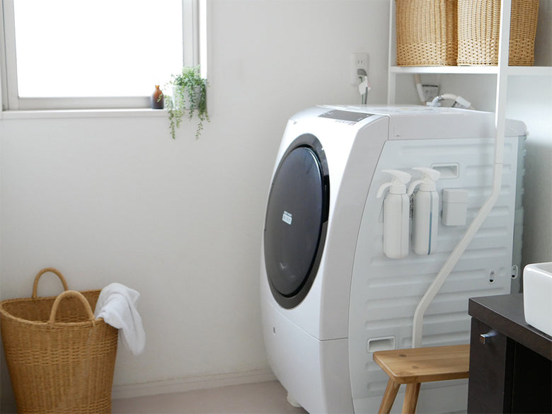 クレエ ユティルの洗えるナイールバスケットがリビングルームの木製床の上に家電製品と共に置かれている様子