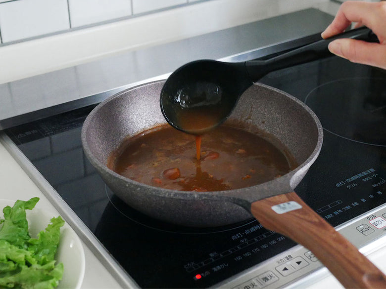 協和工業のムテキバリアフライパンセット20cmと24cmがキッチンカウンターに並び、調理用スプーンや食材と共に配置されている