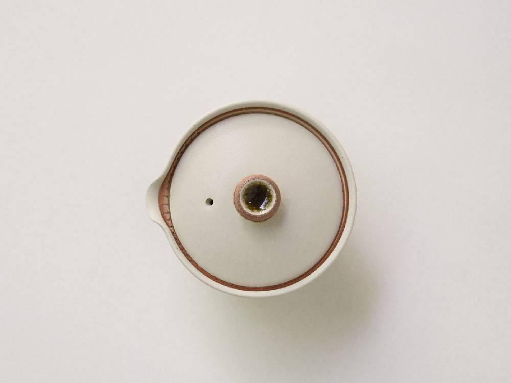 白と黒の陶器製急須と小茶碗が銅のアクセントとともに美しくセットされた日本製ティーウェア