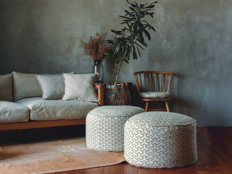 灰色のリネン製フレンチビーズクッションが木目調の家具と共にリビングルームに配置されています。