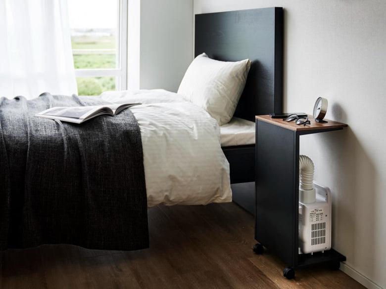 キャスター付き目隠し布団乾燥機スタンドが配置された木製ベッドルームのインテリア