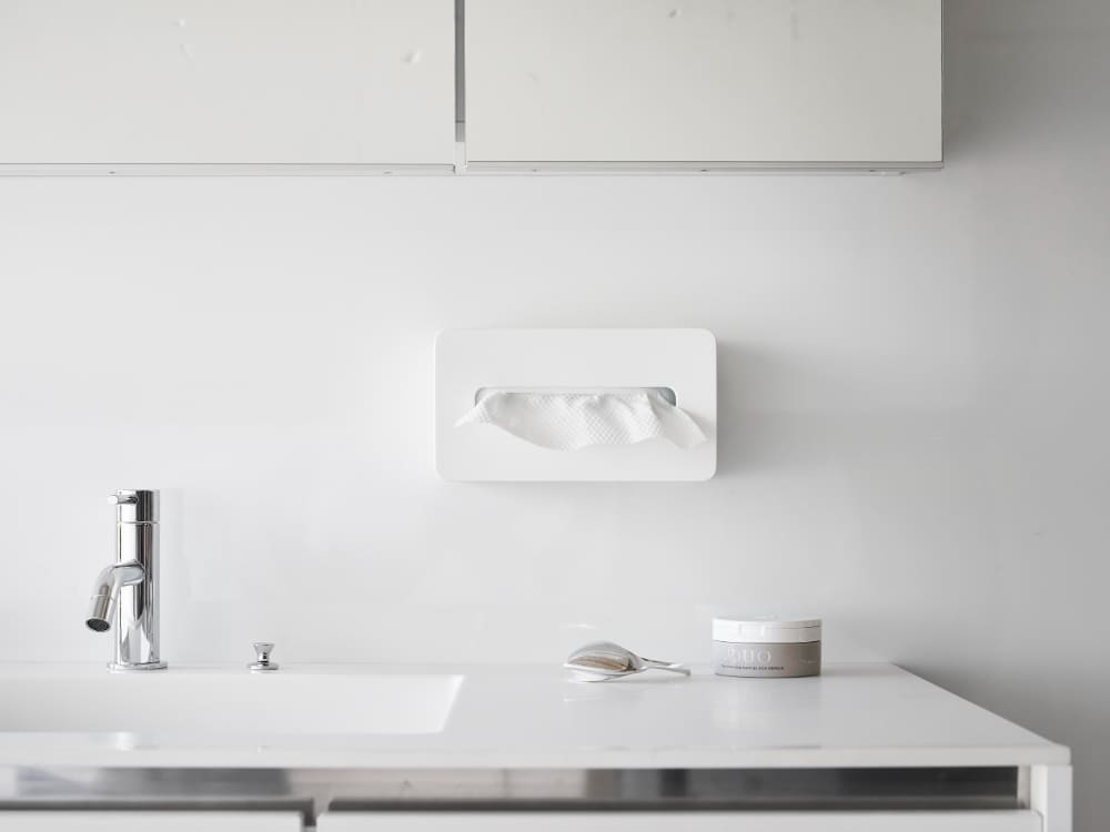 白いバスルームシンクとシルバーの水栓の上に置かれたタワーフィルムフッククレンジングタオルケース