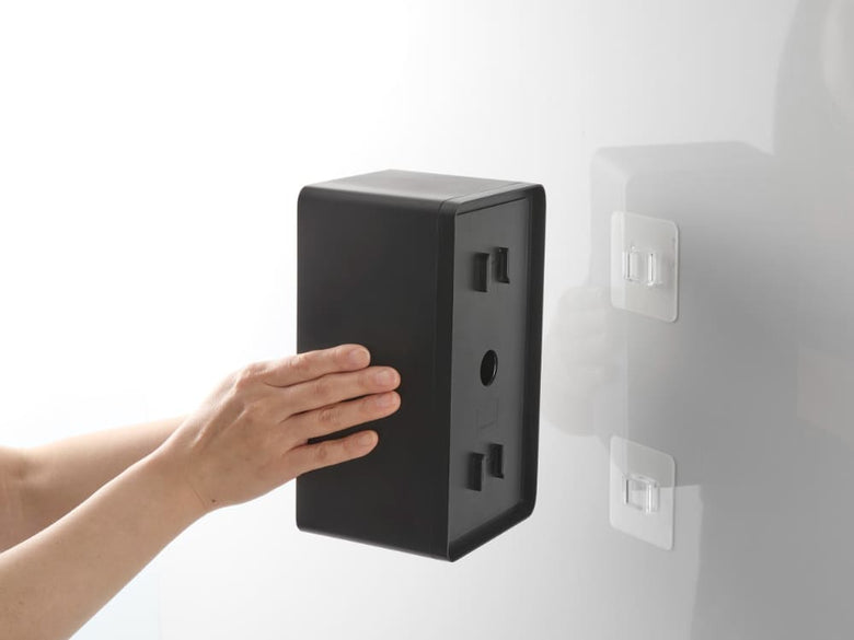 壁に取り付けられたタワー型フィルムフッククレンジングタオルケースと近くのAC電源プラグやスイッチ