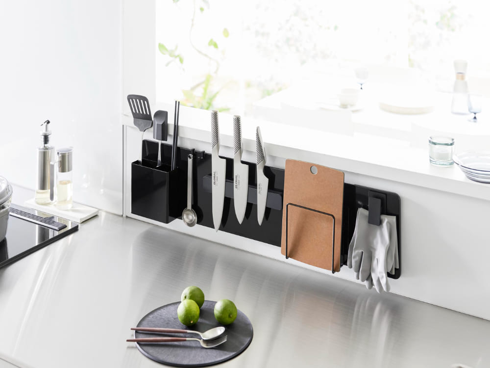 銀色のフィルムフック付きスチールパネルがキッチンに設置され、調理器具や食器、家庭用小物が掛けられている様子