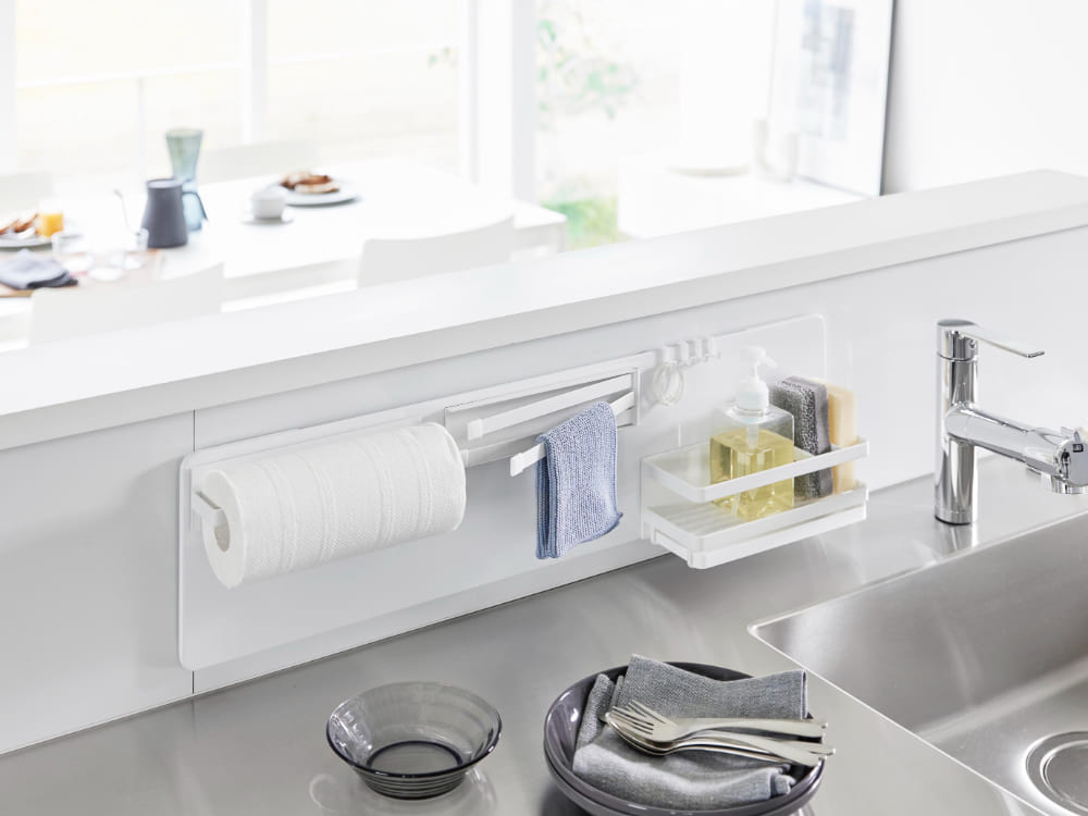 キッチンシンクに取り付けられたタワーフィルムフックスチールパネルと蛇口、ボトルがカウンタートップに配置されている様子