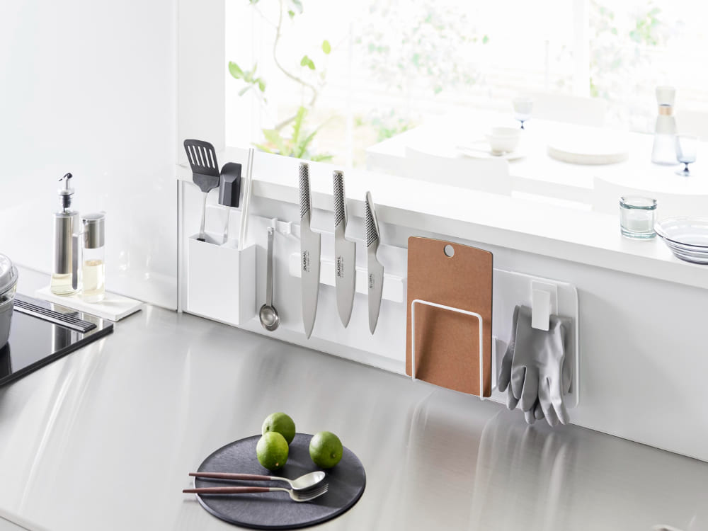 キッチンカウンターに取り付けられたタワータイプのフィルムフックスチールパネルに、調理器具や食器が掛けられている様子