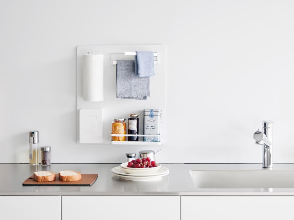 キッチンカウンターに設置されたタワー型スチールフィルムフックパネル。食器やボトル、ソープディスペンサーが整然と掛けられており、シンクや水栓設備と調和しています