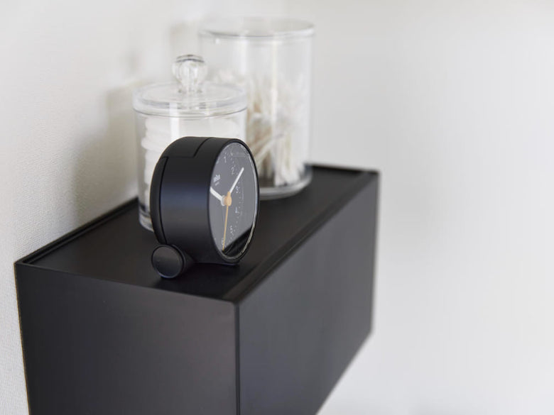 銀色のタワー型ペーパータオルディスペンサーが石こうボードに取り付けられ、観葉植物と共に配置された静物写真