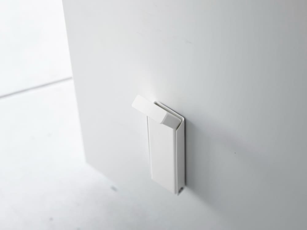 スチール製マグネット折り畳みドアストッパー「tower / タワー」の実物画像。シリコーン滑り止め付きで、磁石を使ってドアを固定するデザイン。