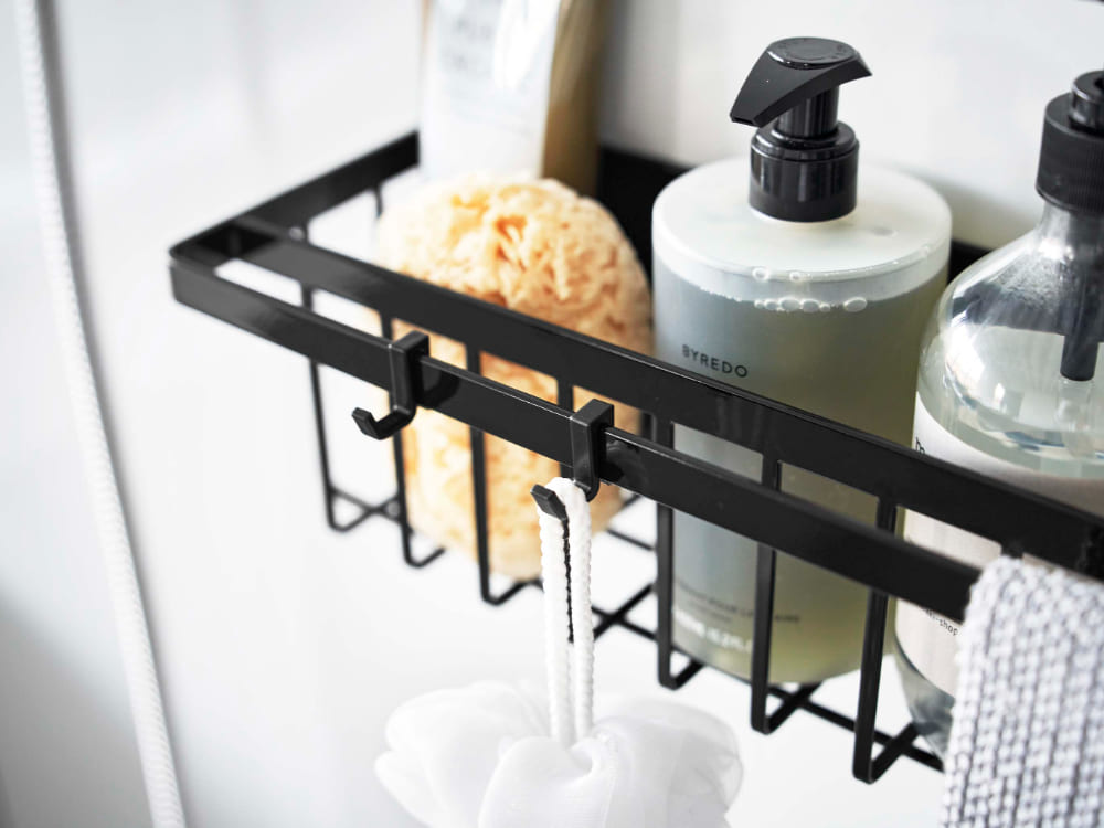 マグネット式タワーバスルームバスケットが壁に設置され、タオルやバス用品を整理している様子。