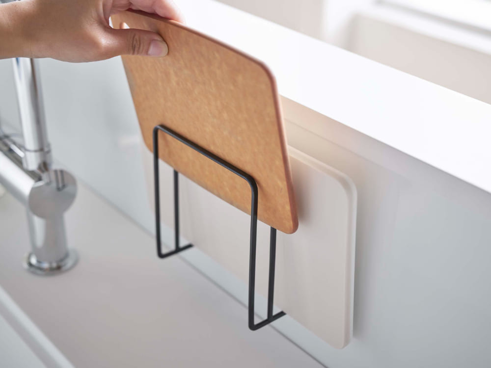 スチール製のタワーマグネットまな板スタンドに複数のまな板が積み重ねられ、キッチンの平らな金属壁面に固定されている様子