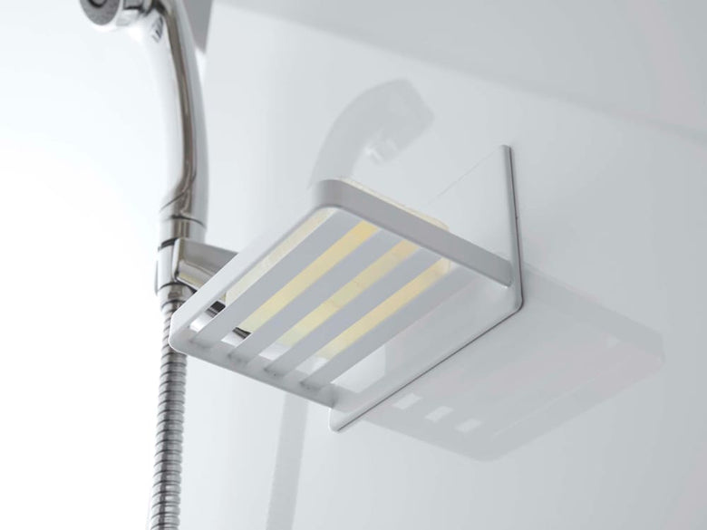 スチール製マグネットバスルームソープトレーが金属の壁面に取り付けられ、明るい照明とシャワーヘッドが周囲に配置されたバスルームの様子