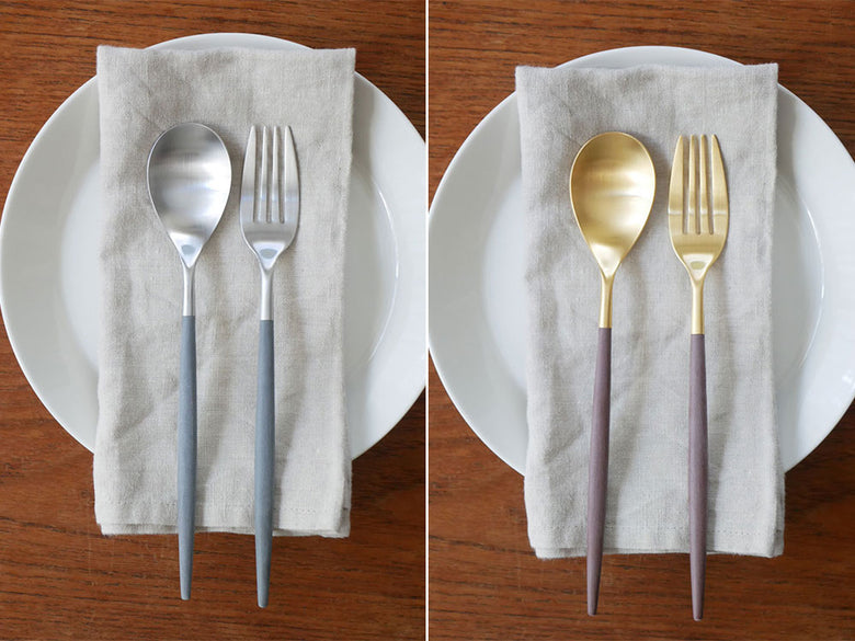 クチポールMIOカトラリーセットのブラウンゴールド色のフォーク、スプーン、ナイフがテーブルクロス上に並べられたディナーセッティングの写真