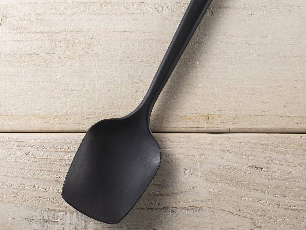 シリコーンゴム製のシリコーンスプーン。木製の背景に持ち手部分が見えるキッチン用調理器具。