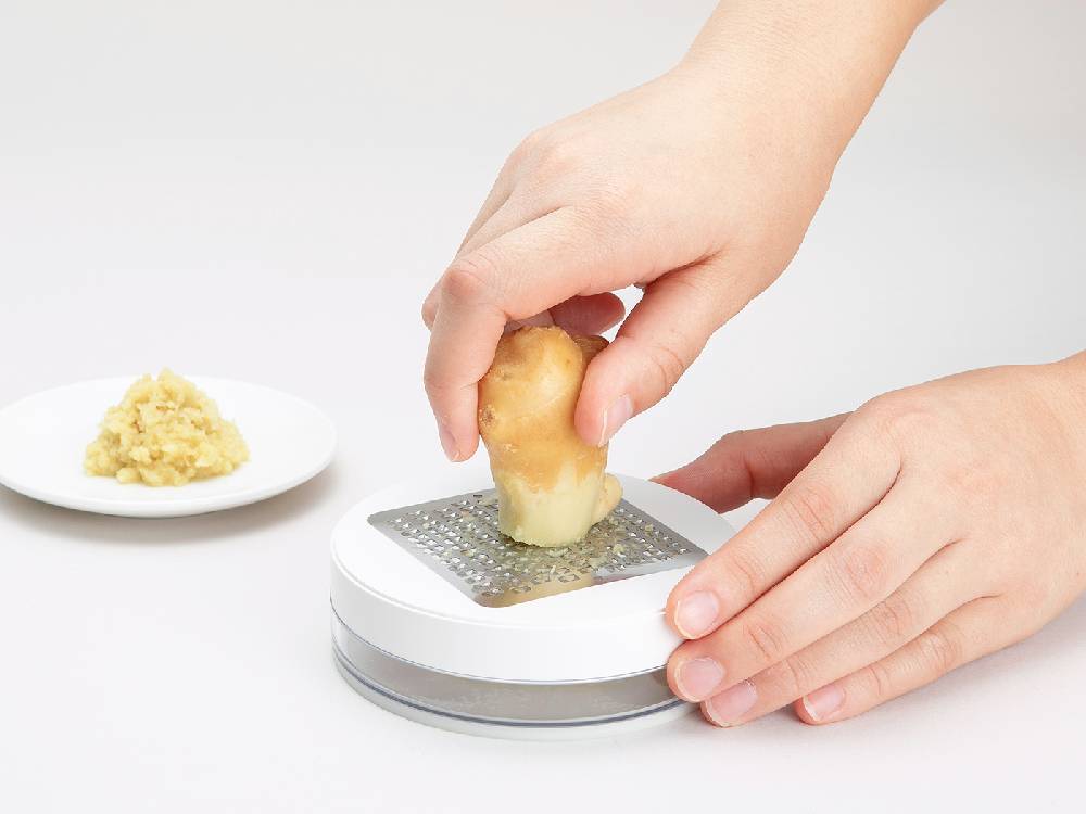 セレクト100 薬味おろしがチーズやパンとともにまな板の上に置かれたキッチン用具の画像